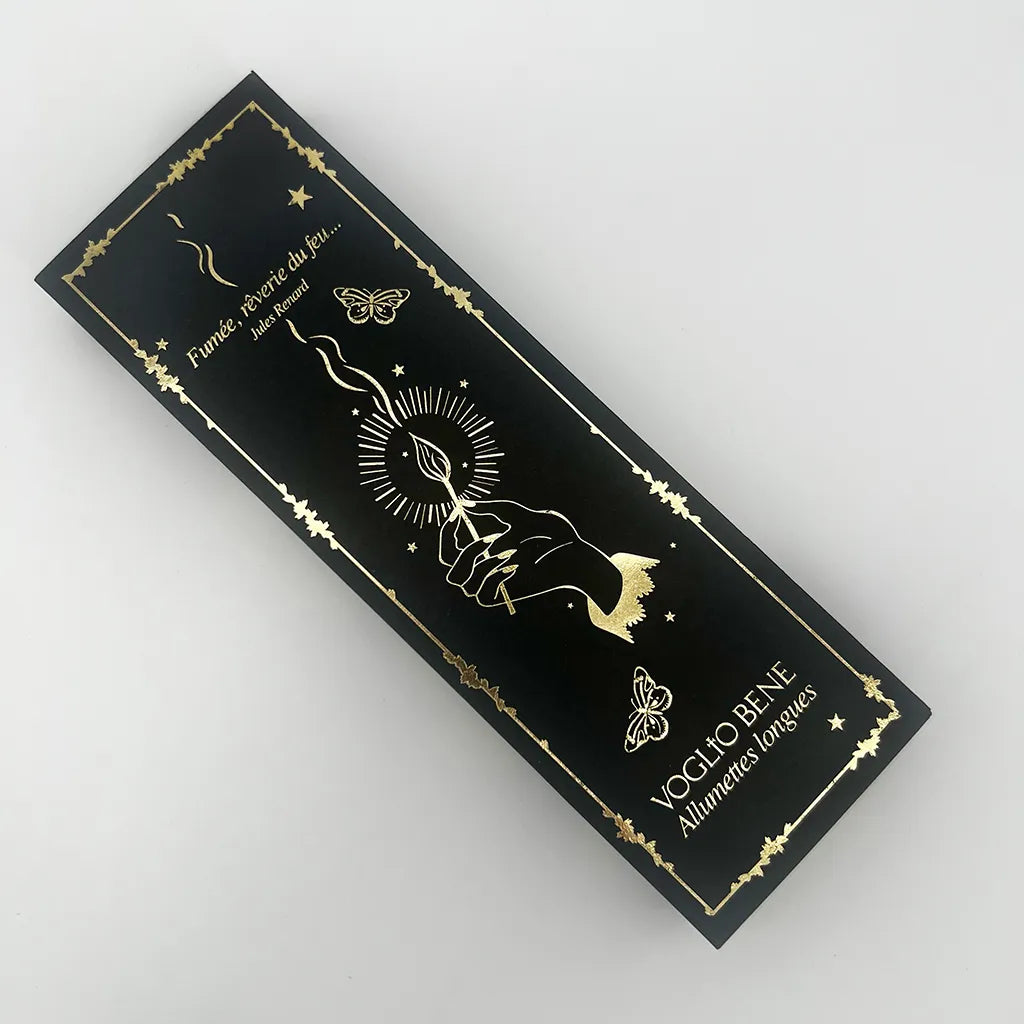 Dos de la boîte d'allumettes à voeux VOGLIO BENE avec inscriptions et logo couleur or sur fond noir.