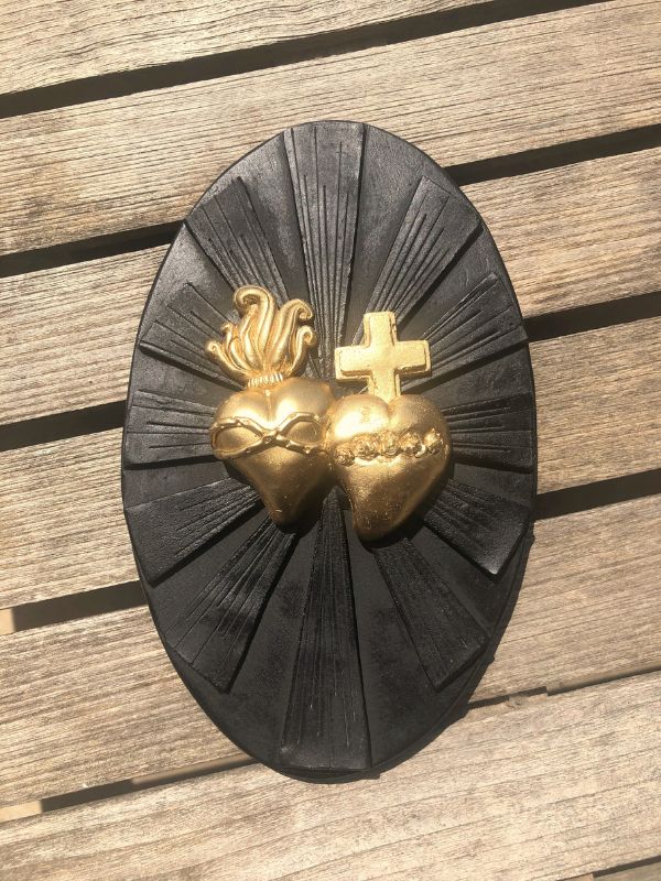 Ex-voto "Toi et moi" avec deux coeurs or avec croix et flammes sur plateau noir.