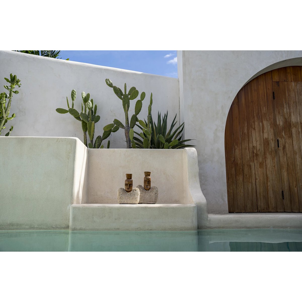 Statuettes posées en extérieur au bord d'une piscine dans un décor bohème balinais. 